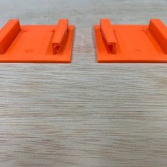 two orange plastic pieces sitting on top of a wooden table