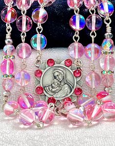 So ethereal, this beautiful fairytale pink rosary is made completely of smooth round mystic aura Quartz gemstones with aurora borealis Preciosa crystals, and they have a gorgeous blue rainbow that reflects in the light.  This gemstone has a very nice density, so this rosary is perfect if you like your rosary to have some weight to it. All of the prayers are said on the 8mm faceted gemstones, and the Pater prayers are flanked with embellishments and pink Preciosa crystal beads.  I have crystalliz Elegant Pink Rosary Bracelet For Wedding, Elegant Pink Wedding Rosary Bracelet, Pink Round Rosary Bracelet Gift, Pink Beaded Jewelry For First Communion, Pink 8mm Bead Jewelry For Valentine's Day, Pink 8mm Beads Jewelry For Wedding, Pink Spiritual Jewelry For First Communion, Pink Rosary, Mystic Quartz