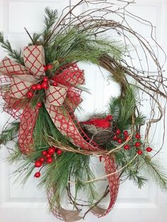 a wreath with red berries and green branches on the front door is adorned with an ornament