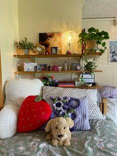 a stuffed animal sitting on top of a bed next to pillows and plants in a bedroom