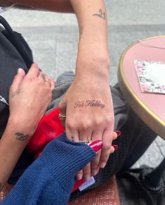 two people holding hands with tattoos on their fingers and the word love is written in cursive writing