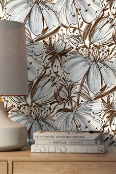 a lamp sitting on top of a wooden dresser next to a wallpapered wall