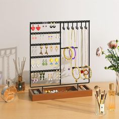 a wooden table topped with lots of jewelry on display next to vase filled with flowers