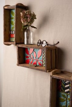 two wooden shelves with painted designs and flowers on them, one shelf is holding a vase