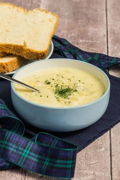 there is a bowl of soup with bread on the side and a blue napkin next to it