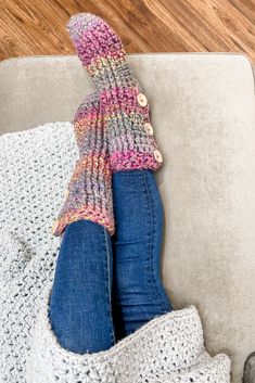 a woman's feet in a knitted sweater and jeans sitting on a couch