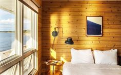 a bedroom with wood paneling and white bedding next to a window overlooking the ocean