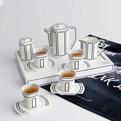 there are cups and saucers on the tray next to each other with tea in them