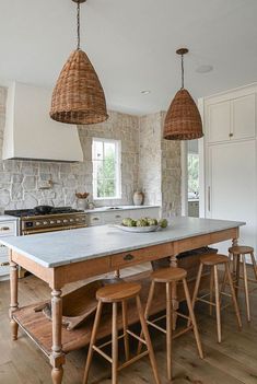 a large kitchen island with two baskets hanging from it's ceiling and an oven in the background