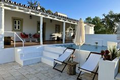 two lawn chairs sitting on top of a patio next to a swimming pool