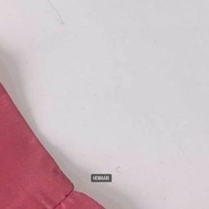 a close up of a pink shirt on a white surface with the word haama written across it