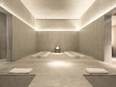 an empty room with benches and lights on the ceiling is lit by recessed lighting