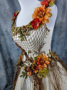 a white dress with orange flowers and leaves on the front, sitting on a mannequin