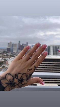 a woman's hand with flowers on it and the city skyline in the background