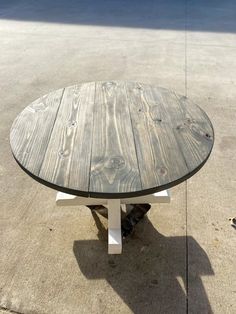 a wooden table sitting on top of a cement floor next to a parking lot with no one around it