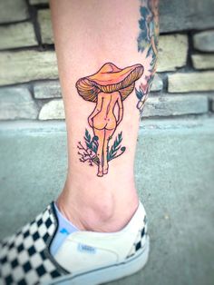 a woman's foot with a mushroom tattoo on her left leg and flowers around the ankles