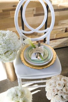 a white chair sitting next to a table with plates and flowers on top of it