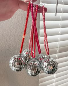 a person holding three disco ball ornaments in their hand