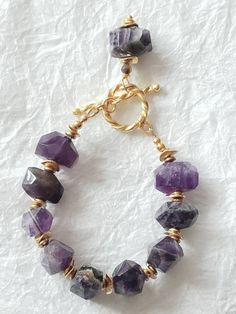 Kingdom of Peace Bracelet Merry & Bright Fall/Holiday 2017 A very royal bracelet. I named this bracelet the "Kingdom of Peace" as the amethyst stone is very well know for it's healing & balancing powers for which brings about peace. It is known as the crown chakra. This bracelet is a classic beauty, effortless style. The amethyst stones warm nicely against the skin and are smooth to the touch. The different striations in each stones really adds gorgeous texture to this bracelet. The stri Peace Bracelet, Amethyst Stones, Fall Holidays, Statement Bracelet, Crown Chakra, White Gift Boxes, Amethyst Stone, Classic Beauty, The Crown