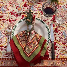 a place setting on a table with red wine and napkins, silverware and utensils