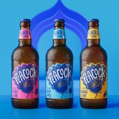 three bottles of beer are sitting on a blue surface with an arch in the background