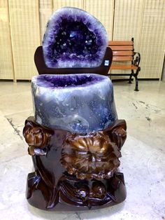 a purple and blue cake sitting on top of a wooden table next to a bench