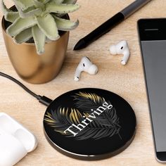 an iphone, headphones and earbuds are on a table next to a plant