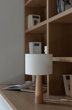 a table lamp sitting on top of a wooden desk next to a bookshelf