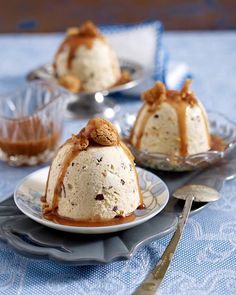 three desserts are sitting on plates with spoons next to them and one is covered in caramel sauce