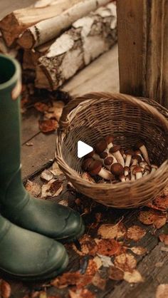 a basket full of mushrooms sitting next to a person's boots on the ground