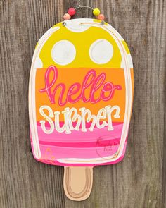 an ice cream popsicle with the words hello summer on it hanging from a wooden fence