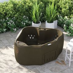 an outdoor hot tub in the middle of a patio with potted plants next to it