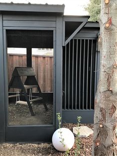 a white ball sitting in front of a wooden structure next to a tree and fence