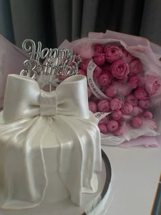 a birthday cake and bouquet of pink roses