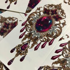 several cards with designs on them, including an oval shaped purple stone surrounded by smaller red and white jewels