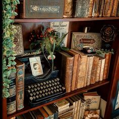 an old fashioned typewriter sitting on top of a wooden book shelf filled with books