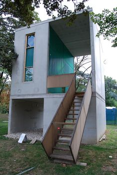 a concrete structure with stairs leading up to the upper floor and second story window above it