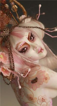 a close up of a doll with pink hair and makeup