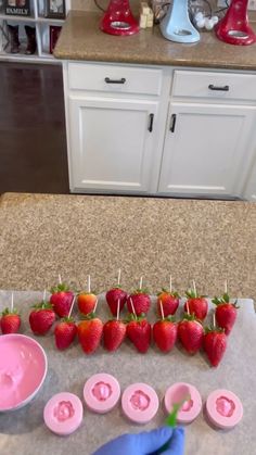 strawberries are arranged on toothpicks with pink icing