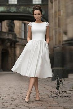 a woman in a white dress is walking down the street