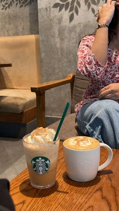 a woman sitting at a table with a cup of coffee