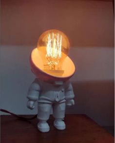 an astronaut lamp sitting on top of a wooden table next to a white light bulb