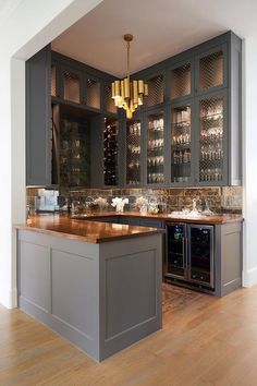 a kitchen with grey cabinets and wooden counter tops, wine rack in the middle between two bar stools