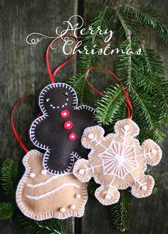 two ornaments hanging from a christmas tree on a wooden surface with the words merry christmas written above them