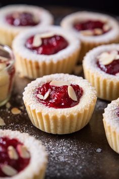 small desserts are sitting on a baking sheet with almonds and raspberry sauce