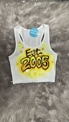 a crop top with the word est 205 printed on it in yellow and black ink