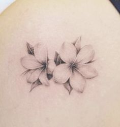 the back of a woman's shoulder with three flowers on her left side tattoo