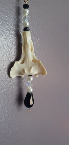 a clock made out of bone and beads hanging from a hook on the wall in a room