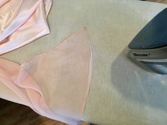 an ironing board and some pink fabric on a table with a piece of cloth next to it