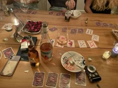 people sitting at a table with cards and wine on it, one person holding a cell phone